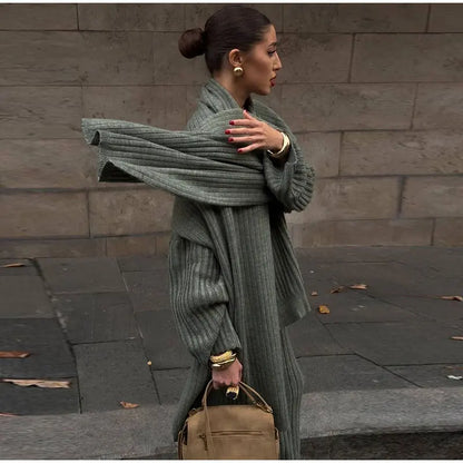 Woman in burgundy ribbed knit sweater and wide leg pants carrying a brown suede bag.