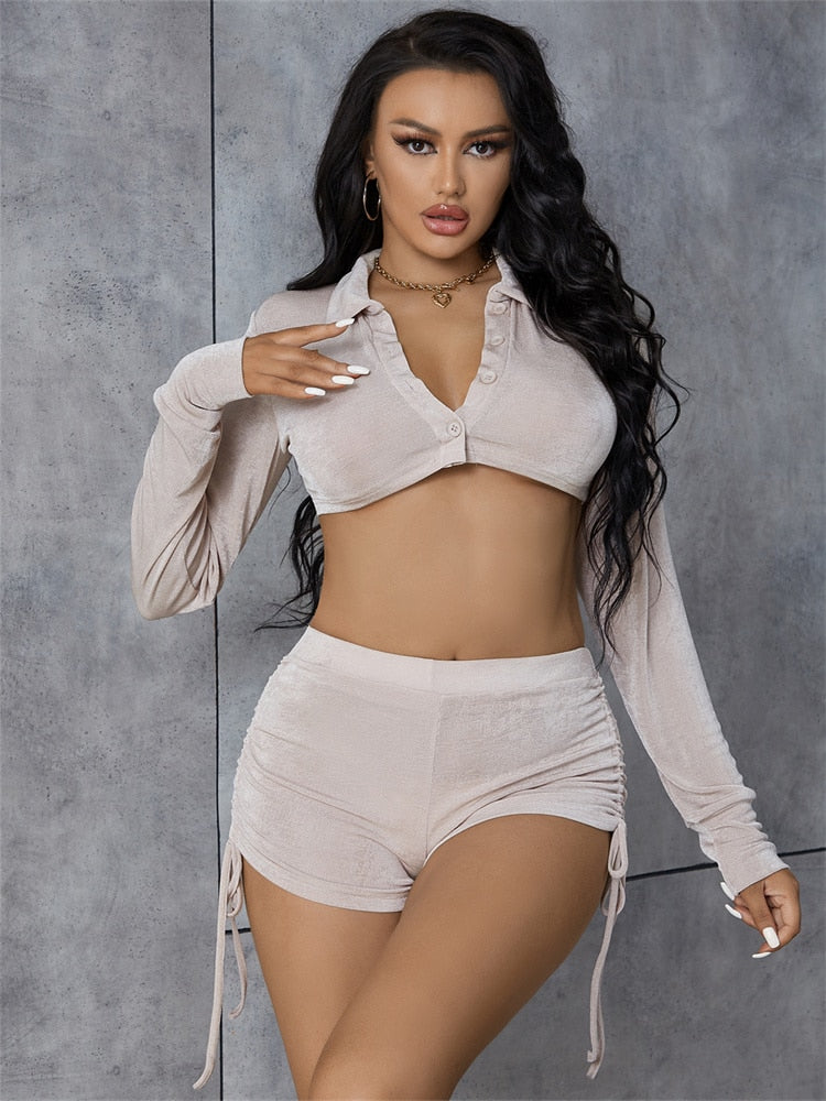 Woman in beige shimmer knit cropped shirt and ruched shorts.
