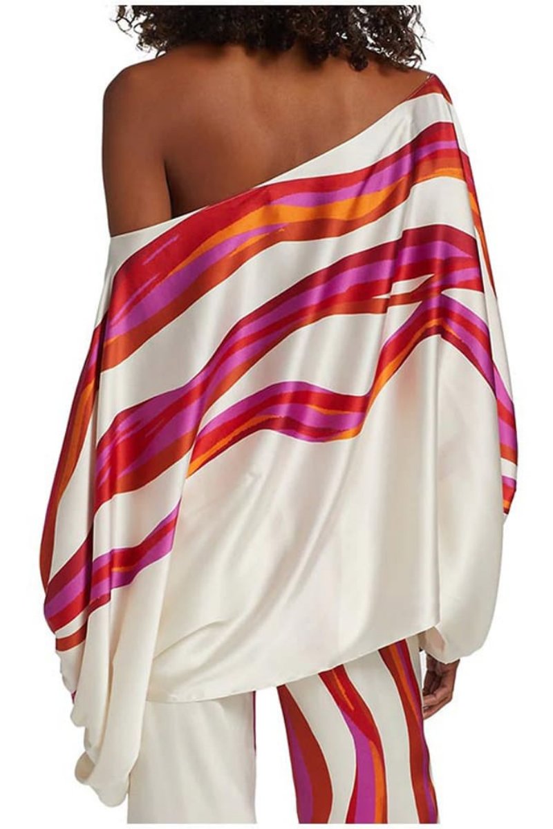 Woman in ivory satin pant set with pink and orange wave print