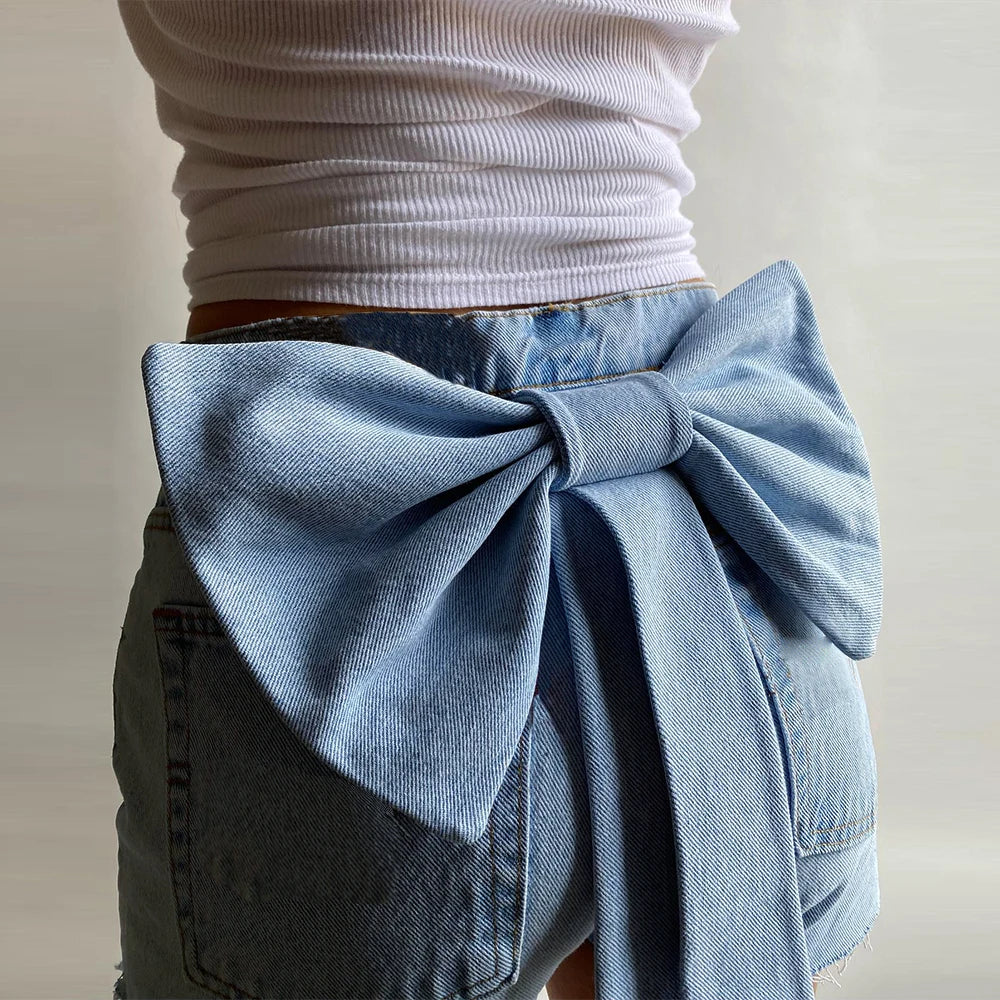 Back view of light wash denim shorts with large bow detail