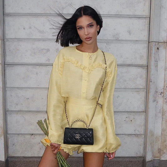 Woman in yellow linen romper with black quilted handbag