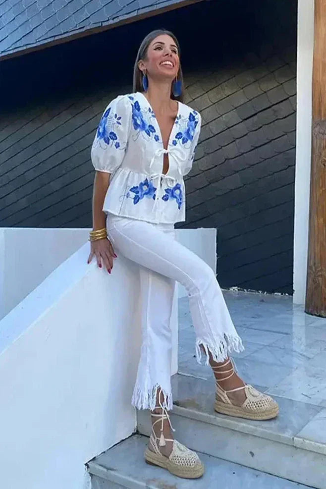 Woman in white linen blouse with blue and yellow floral embroidery