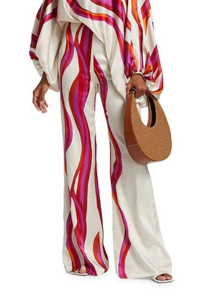 Woman in ivory satin pant set with pink and orange wave print