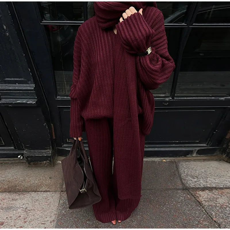 Woman in burgundy ribbed knit sweater and wide leg pants carrying a brown suede bag.