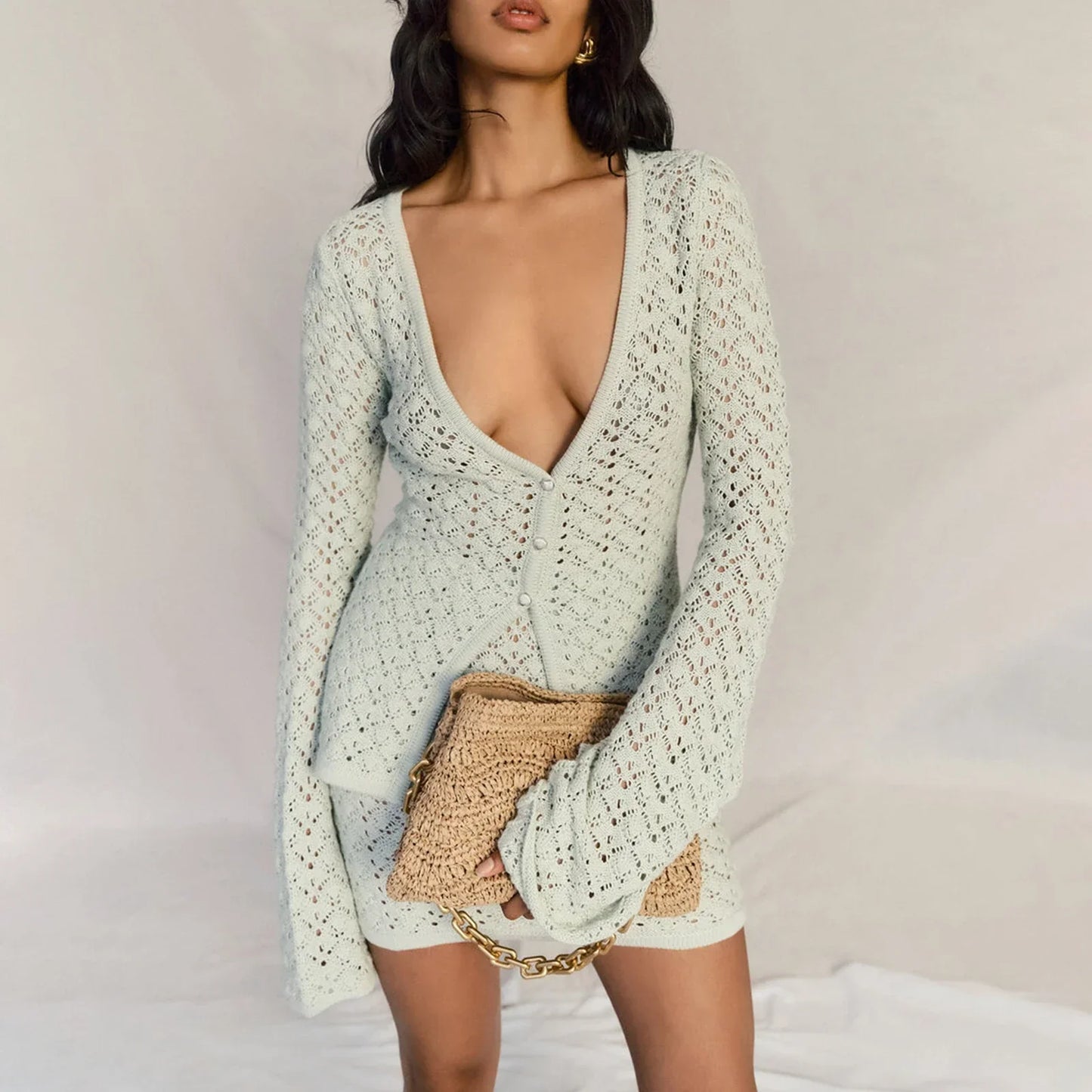 Woman wearing a white crochet knit cardigan and skirt set.