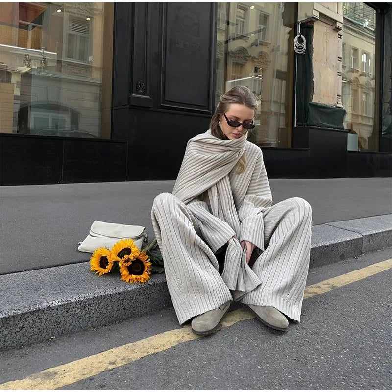 Woman in burgundy ribbed knit sweater and wide leg pants carrying a brown suede bag.