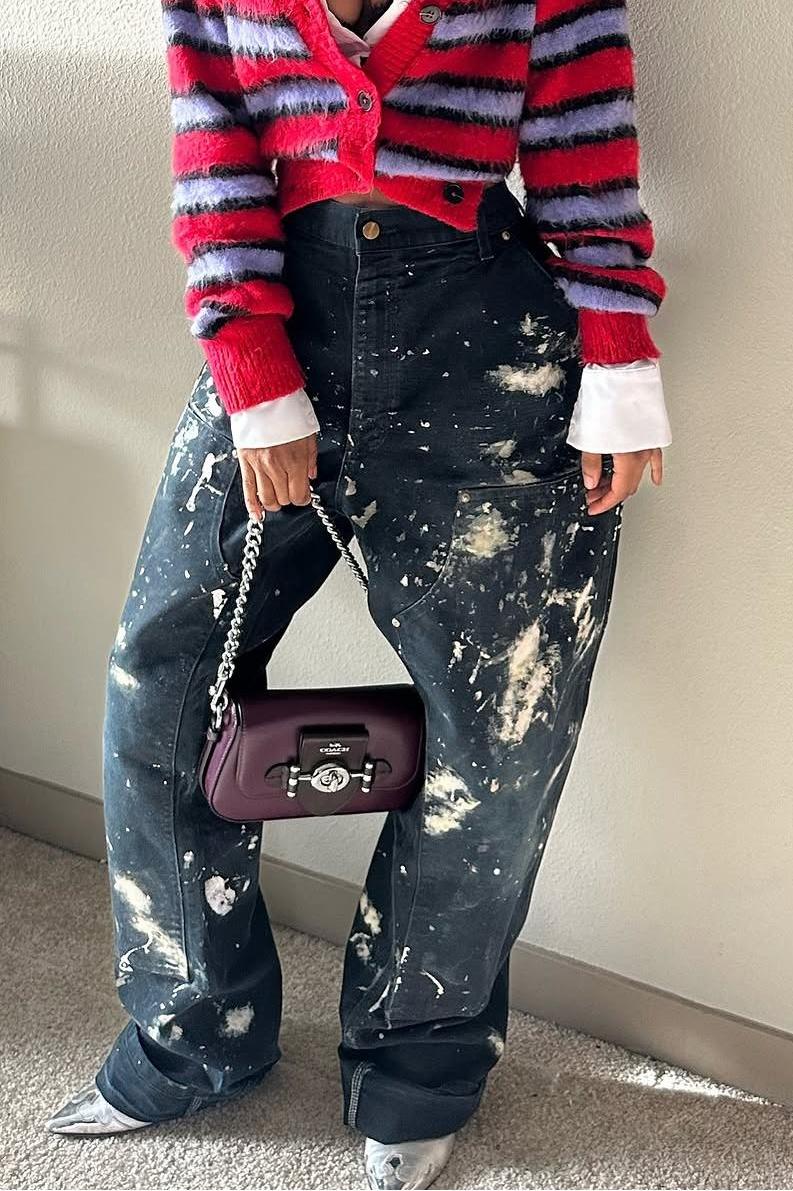 Woman wearing red and lavender striped fuzzy cardigan with paint-splattered jeans.
