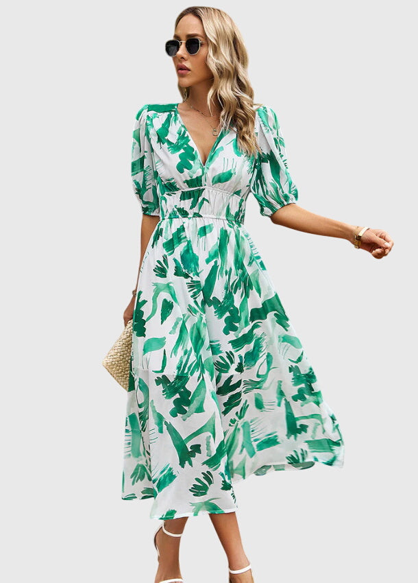 Green - A woman wearing a vibrant multi-color abstract floral print chiffon midi dress with puff sleeves, a V-neckline, and a smocked waist, paired with white heeled sandals.