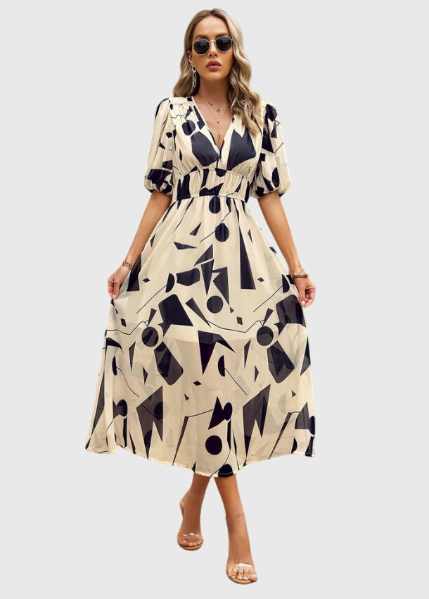 Apricot - A woman wearing a vibrant multi-color abstract floral print chiffon midi dress with puff sleeves, a V-neckline, and a smocked waist, paired with white heeled sandals.