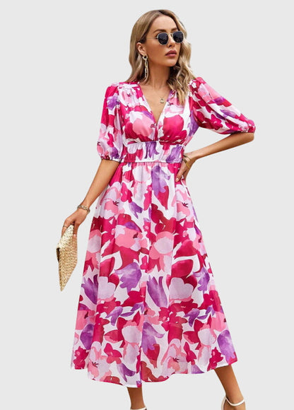 Pink - A woman wearing a vibrant multi-color abstract floral print chiffon midi dress with puff sleeves, a V-neckline, and a smocked waist, paired with white heeled sandals.