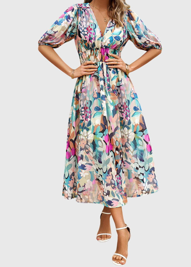 Floral - A woman wearing a vibrant multi-color abstract floral print chiffon midi dress with puff sleeves, a V-neckline, and a smocked waist, paired with white heeled sandals.