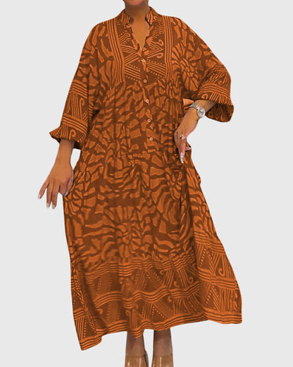 Orange - A woman wearing a vibrant pink and light pink abstract floral print maxi dress with long sleeves, a split V-neckline, and a tiered skirt featuring geometric border patterns.