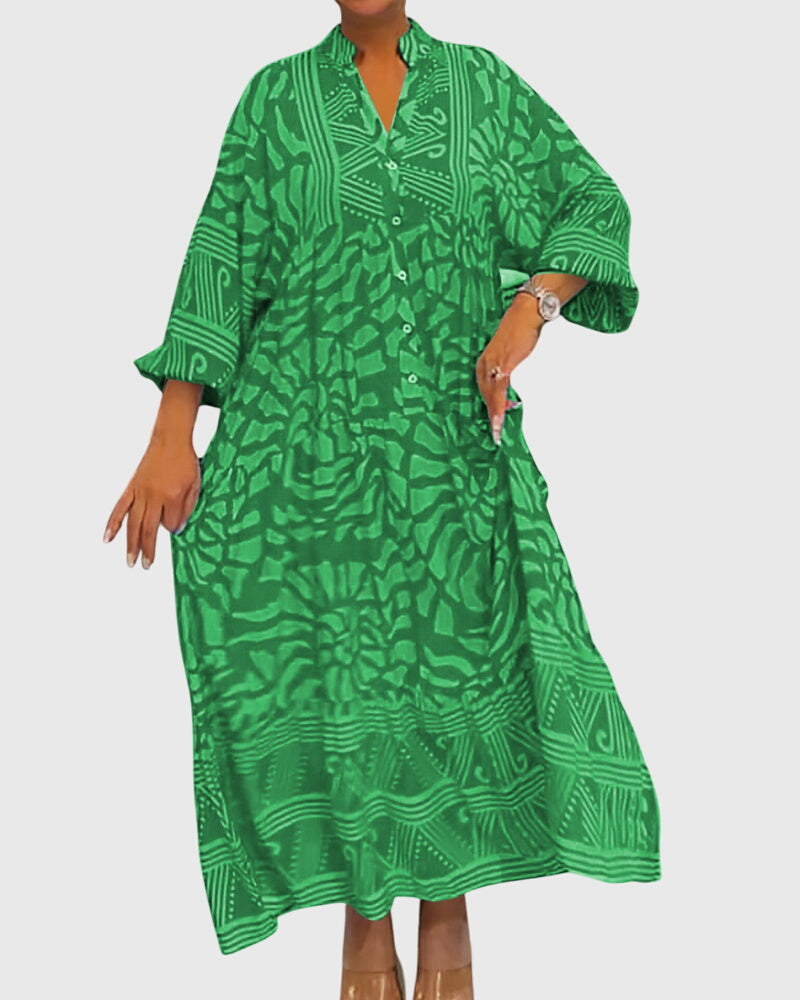 Green - A woman wearing a vibrant pink and light pink abstract floral print maxi dress with long sleeves, a split V-neckline, and a tiered skirt featuring geometric border patterns.