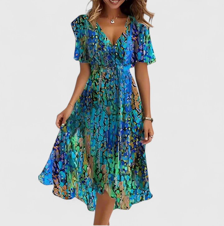 Blue/Green - A woman wearing a V-neck midi dress featuring a vibrant blue and green abstract mosaic print, short flutter sleeves, and a flowing A-line skirt.