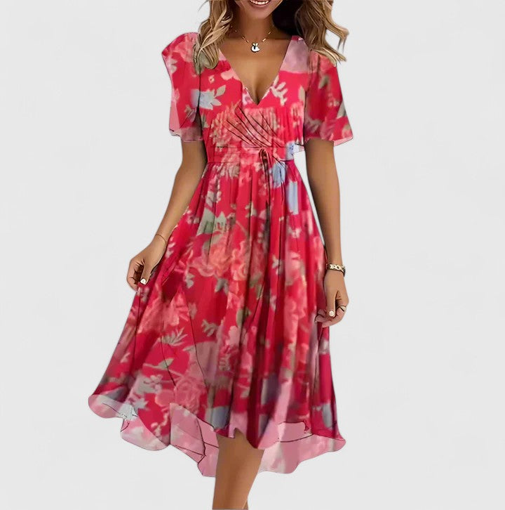 Red - A woman wearing a V-neck midi dress featuring a vibrant blue and green abstract mosaic print, short flutter sleeves, and a flowing A-line skirt.