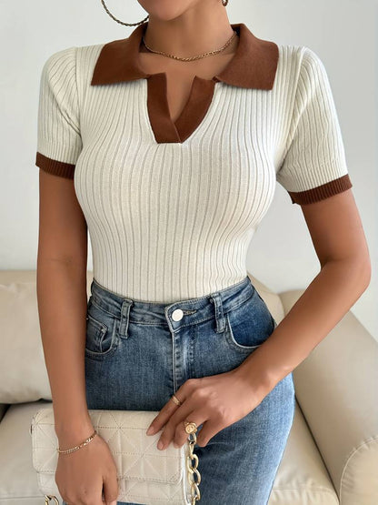 Woman in cream ribbed knit polo shirt with brown trim detail holding a white cup.