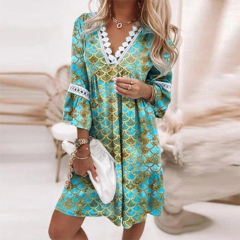 Green - A woman wearing a white mini sundress with a blue Mediterranean botanical print, featuring a V-neckline with white crochet lace trim and 3/4 bell sleeves with lace inserts.