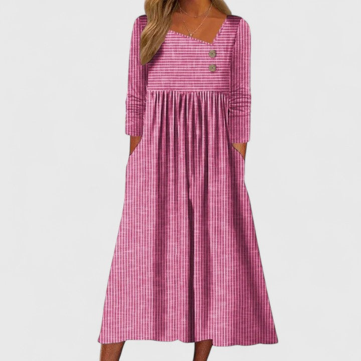 Pink - A woman wearing a gray and white vertically striped midi sundress with three-quarter sleeves, an asymmetric neckline featuring two decorative buttons, an empire waist, and side pockets.