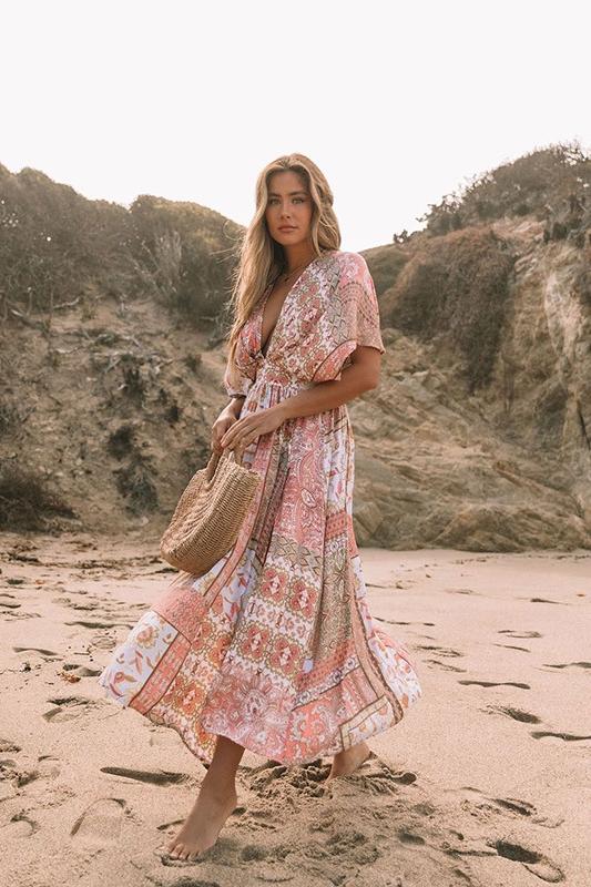 Woman in peach floral maxi dress on beach