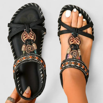 Graphite Black - Faux-leather flat slingback sandals featuring a beaded medallion centerpiece, embroidered instep strap, and contrast stitching along the sole edge.