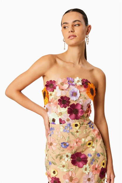 Woman in strapless tulle midi dress with colorful floral appliqués