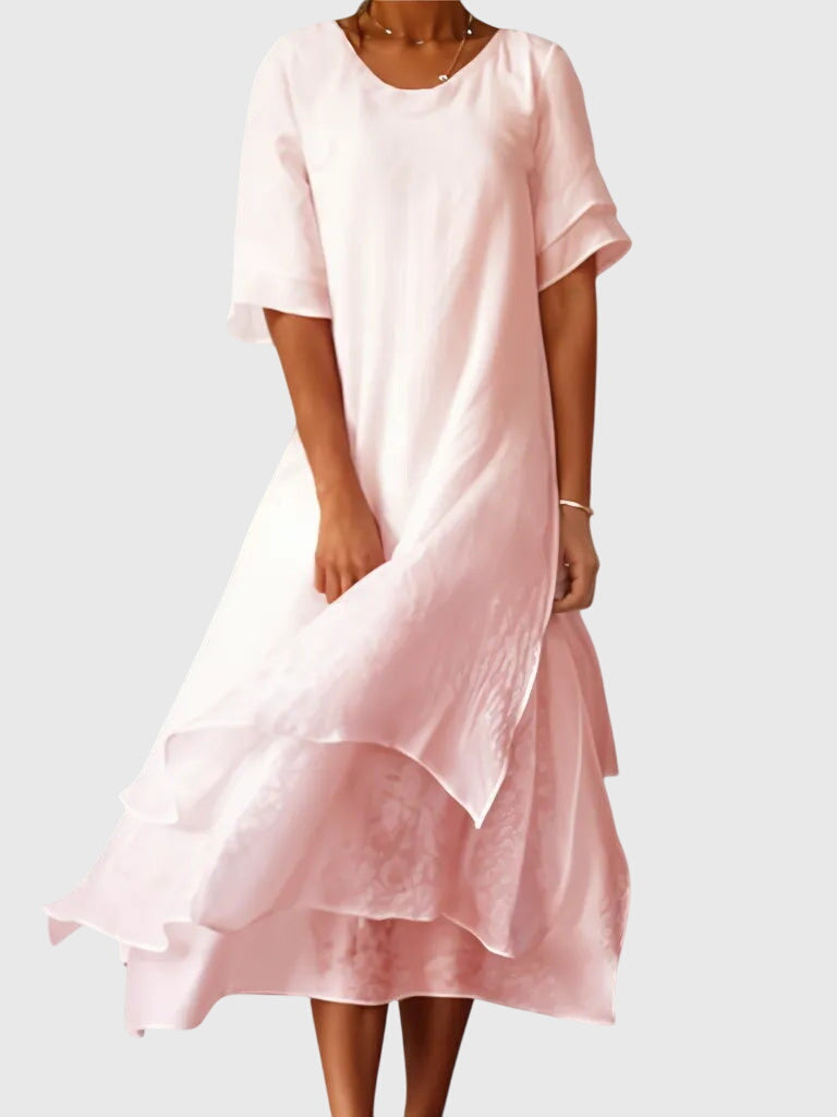 Pink - A woman wearing a light pink, double-layered chiffon midi dress with short sleeves, a scoop neck, and a flowy asymmetric hemline.