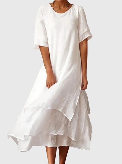 White - A woman wearing a light pink, double-layered chiffon midi dress with short sleeves, a scoop neck, and a flowy asymmetric hemline.