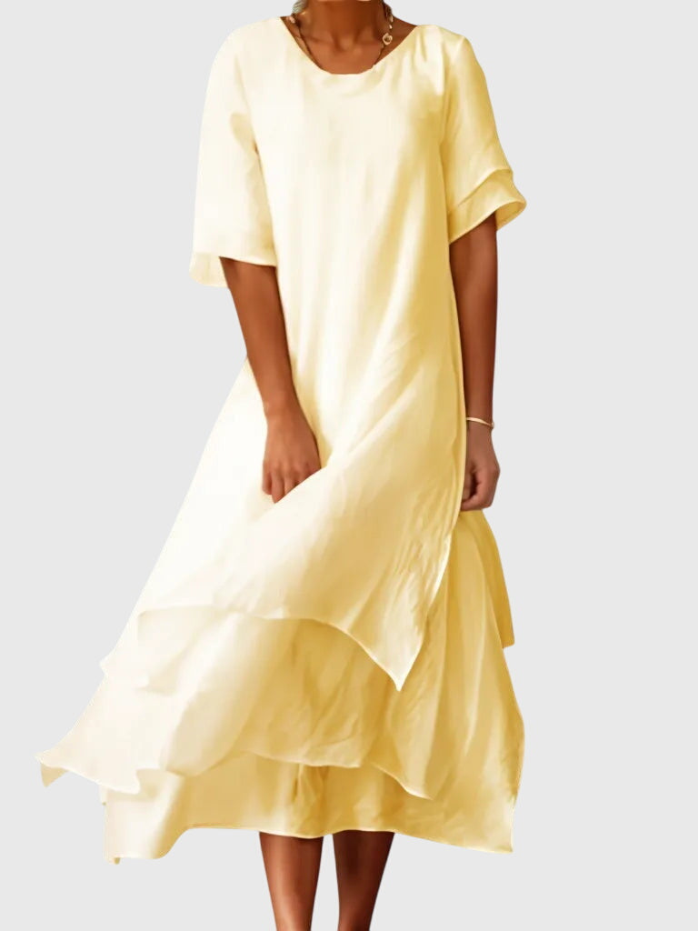 Yellow - A woman wearing a light pink, double-layered chiffon midi dress with short sleeves, a scoop neck, and a flowy asymmetric hemline.