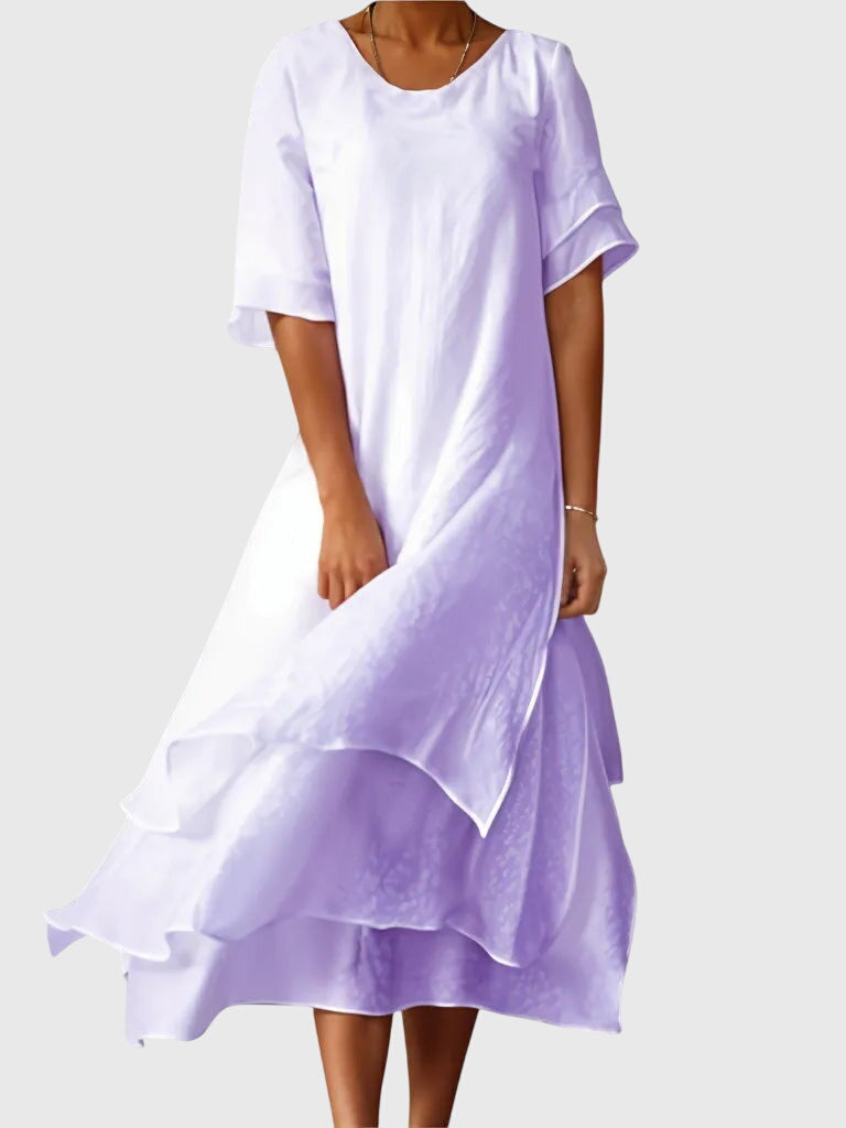 Purple - A woman wearing a light pink, double-layered chiffon midi dress with short sleeves, a scoop neck, and a flowy asymmetric hemline.