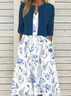 Dark Blue - A woman wearing a dusty blue mock-layered midi dress featuring a solid 3/4-sleeve bodice, a split neckline, and a flowy skirt with a white botanical branch print.