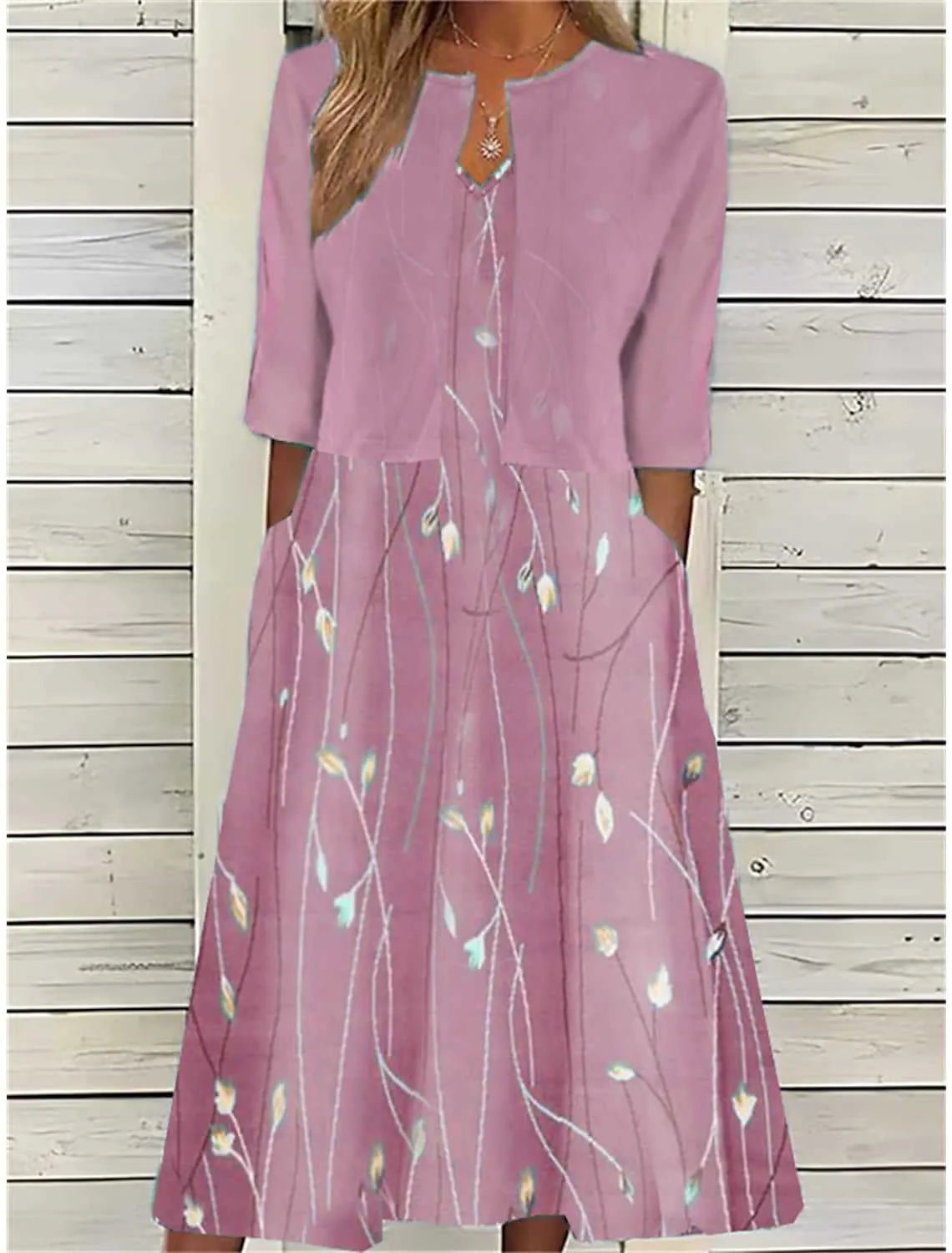 Pink - A woman wearing a dusty blue mock-layered midi dress featuring a solid 3/4-sleeve bodice, a split neckline, and a flowy skirt with a white botanical branch print.