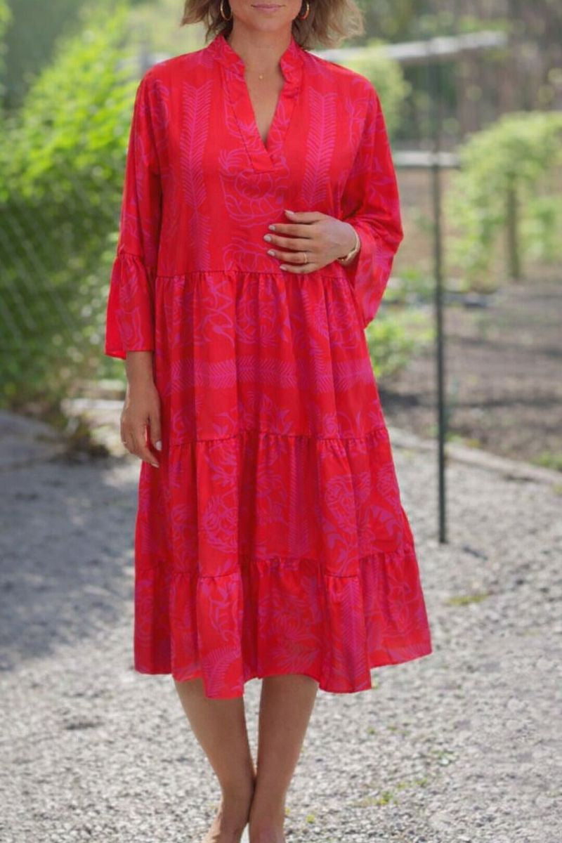 Red - A woman wearing a vibrant red and pink tropical botanical print midi sundress with three-quarter bell sleeves, a split V-neckline, and a tiered flowy skirt.
