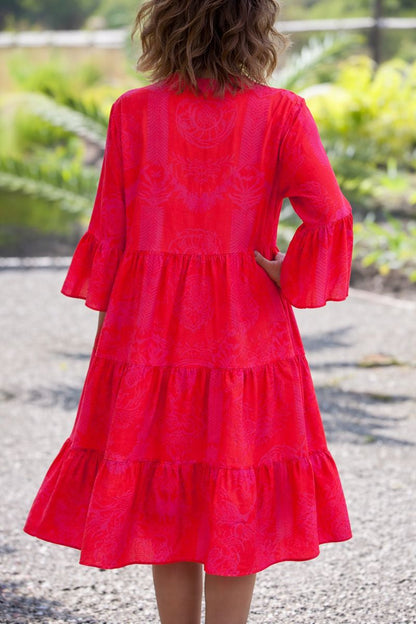 Red - A woman wearing a vibrant red and pink tropical botanical print midi sundress with three-quarter bell sleeves, a split V-neckline, and a tiered flowy skirt.