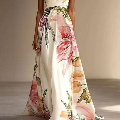 Cream - A woman wearing a floor-length satin halter maxi dress featuring a large-scale watercolor botanical print in pink, orange, and green on an ivory background, showcasing a pleated waist and a flowing A-line silhouette.