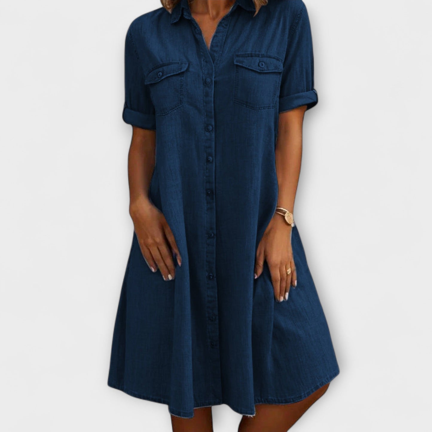 Navy Blue - A woman wearing a light blue chambray short-sleeve button-down sundress with chest pockets and a relaxed fit.