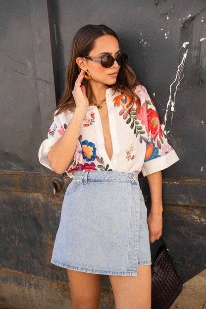 Woman in white linen shirt with colorful floral embroidery