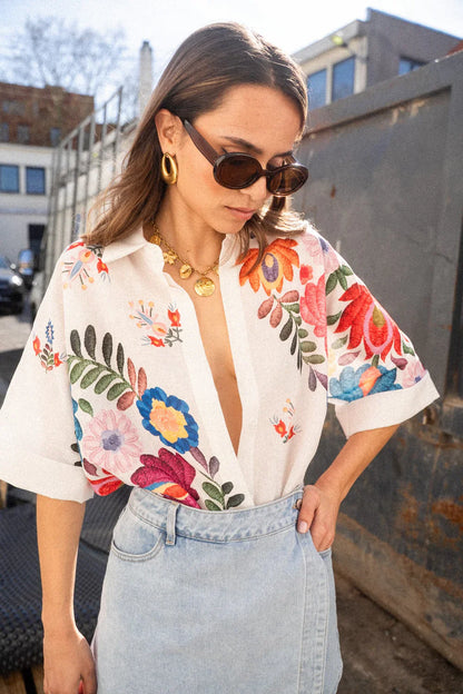 Woman in white linen shirt with colorful floral embroidery