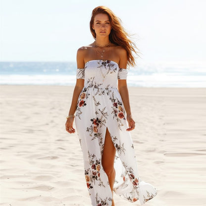White - A woman standing on a sandy beach wearing a white off-the-shoulder chiffon maxi dress with a botanical floral print, featuring a smocked bodice and a high thigh slit.
