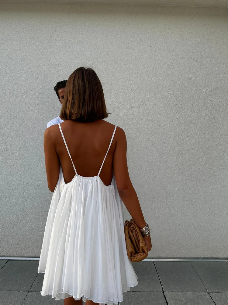 3XL - Woman wearing a short, flowy chiffon babydoll mini sundress with spaghetti straps and a gathered neckline, standing outdoors near an ocean
