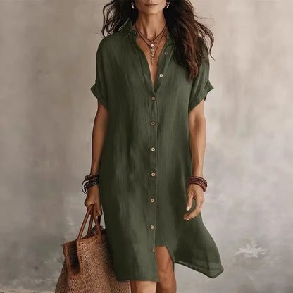 Army green - A woman wearing a black, short-sleeved linen midi shirt dress with a button-down front, styled with a woven straw tote bag.