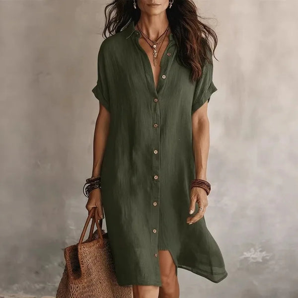 Army green - A woman wearing a black, short-sleeved linen midi shirt dress with a button-down front, styled with a woven straw tote bag.