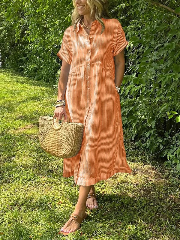 Orange - A woman wearing a blue and white vertically striped linen-blend midi shirt dress with short sleeves, a pointed collar, and a button-down front, holding a woven straw bag in a grassy outdoor setting.