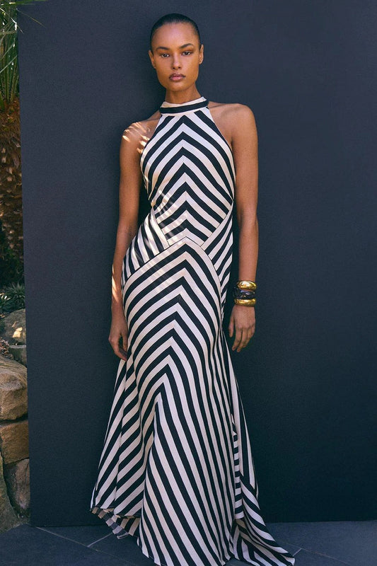 Woman in black and white striped halter neck satin maxi dress
