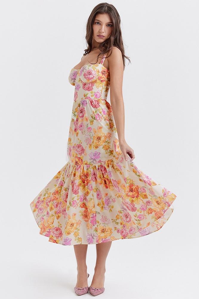 Woman in floral print sundress leaning on stone wall