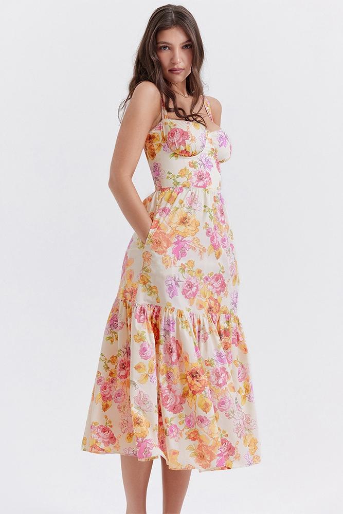 Woman in floral print sundress leaning on stone wall