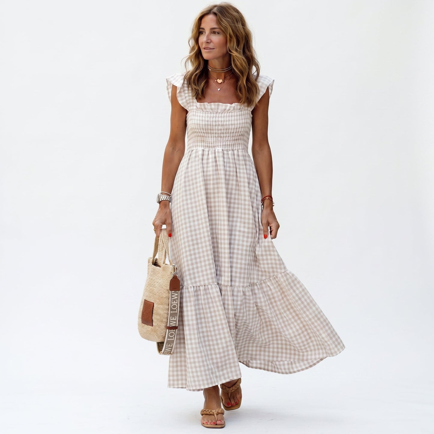 Beige - Woman wearing a gingham smocked maxi dress with flutter sleeves and a tiered skirt on a white background