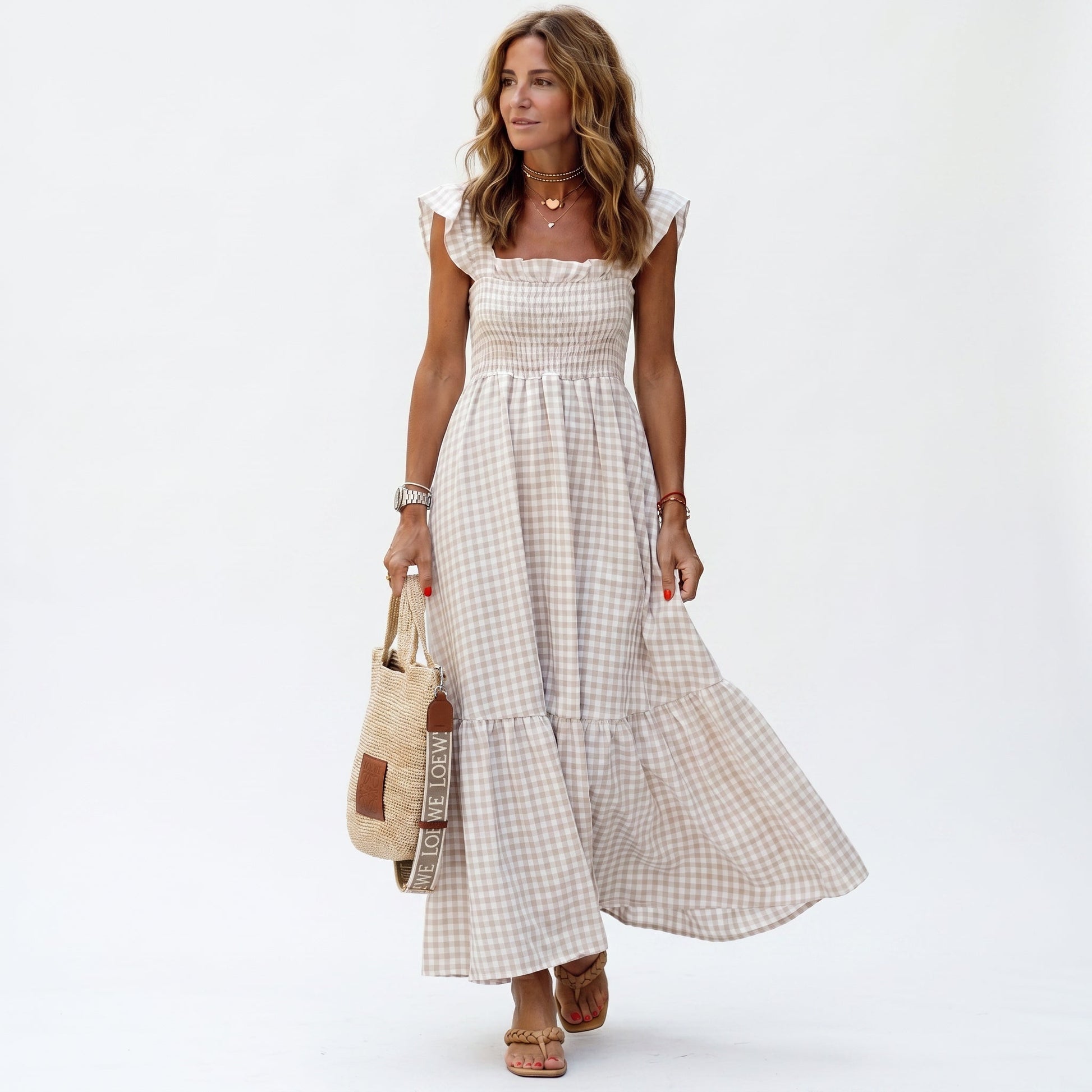 Beige - Woman wearing a gingham smocked maxi dress with flutter sleeves and a tiered skirt on a white background