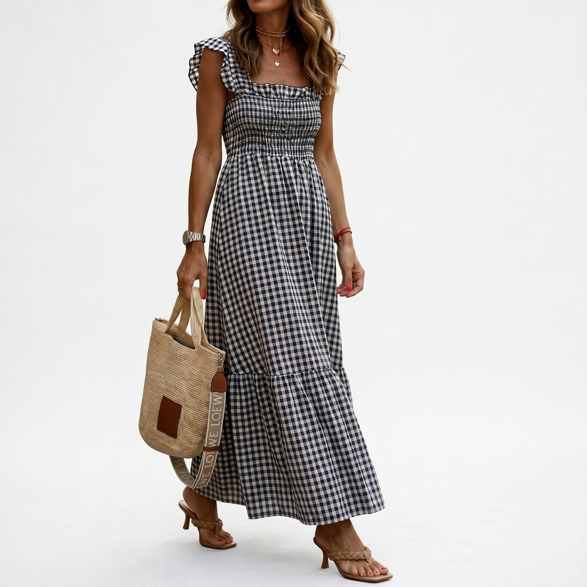 Black - Woman wearing a gingham smocked maxi dress with flutter sleeves and a tiered skirt on a white background