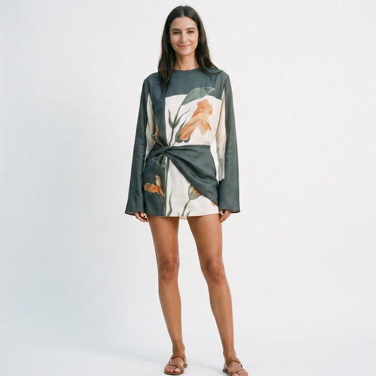 XXL - Model wearing a long-sleeve mini dress featuring a large-scale botanical print, high neckline, and an architectural twisted waist detail.