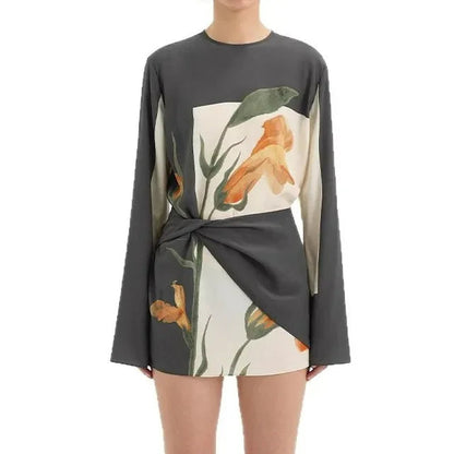 XXL - Model wearing a long-sleeve mini dress featuring a large-scale botanical print, high neckline, and an architectural twisted waist detail.